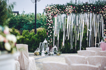 Decorative white lanterns with bouquets stand before wedding alt