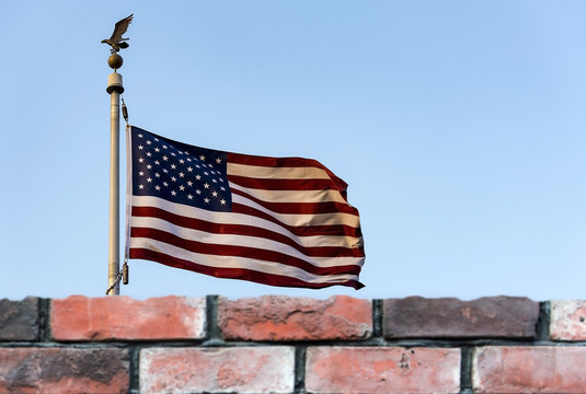 American flag and defocused brick fence, the United States confrontation and refugees