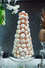 Pyramid made of white eclairs stands on glass dish