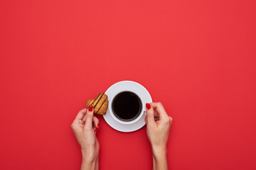 Woman hands holding coffee cup with small biscuit in a form of h