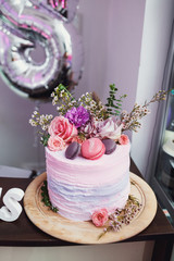 Beautiful cake decorated with roses, greenery and macaroons