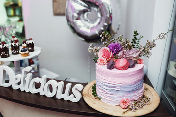 White lettering delicious stands behind beautiful pink cake