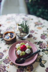 Pink plate with dessert stands on table covered with flowered cl