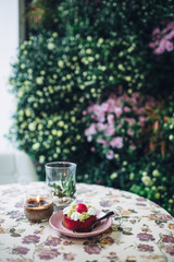 Pink plate with dessert stands on table covered with flowered cl