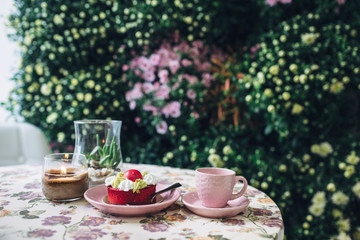 Pink cup and plate with dessert stand on flowered coffee table