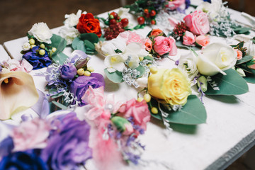 Boutonnieres made of gorgeous flowers lie on white wooden table