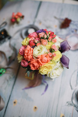 Bouquet of yellow, violet and orange flowers stands on table wit