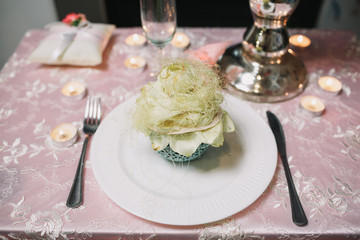 Little glass with rose stands on white plate