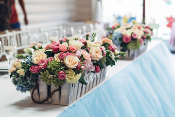 Lots of roses and hydrangeas stand in little wooden boxes on blu