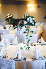 Rose bouquet on tall vase and greenery twined around it