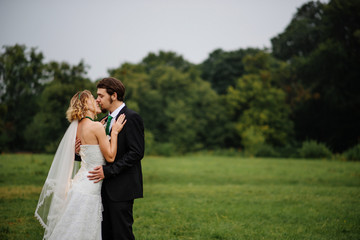 Embracing wedding couple in love on cloudy weather outdoor.