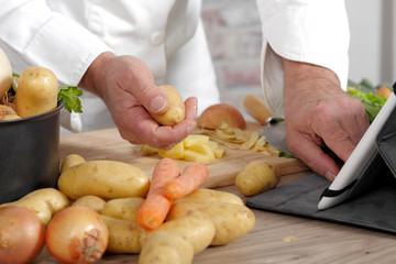 detail of hands of chef using tablet for cooking