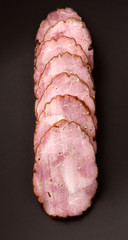Smoked sausage, ham on a dark background