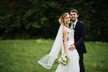 Embracing wedding couple in love on cloudy weather outdoor.