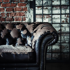 Fototapeta na wymiar Old vintage sofa on background of brick wall and grids, selectiv
