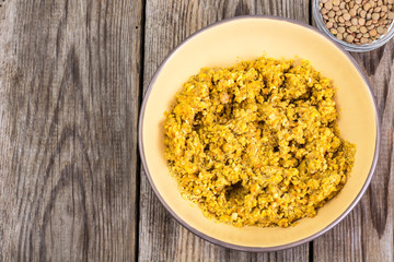 Side dish of lentils with vegetables, butter in bowl on wooden b