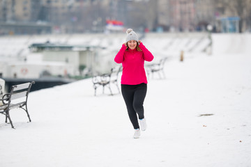 Girl wearing sportswear and running on snow during winter