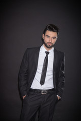 one young man posing suit, looking at camera, black background