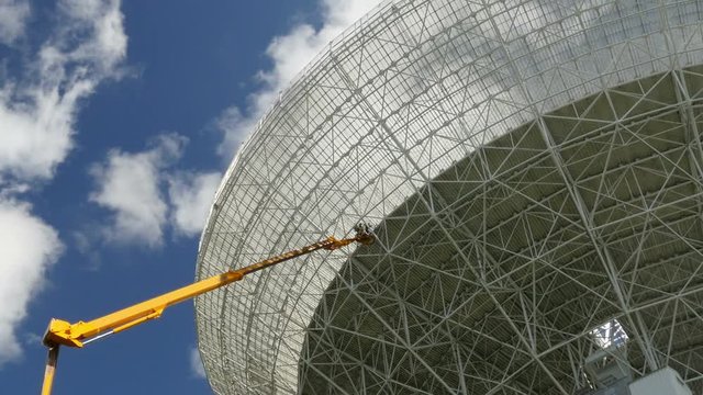 Workers on a crane renovate, painting the Effelsberg 100-m Radio Telescope. Time lapse zoom shot. 11837
