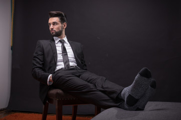 one young man sitting chair relaxing socks suit