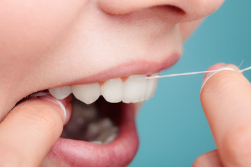 side view woman face smiling with dental floss.