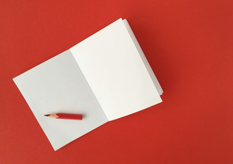 Sheet of blank paper and red pencil. Space for message. Red background. 