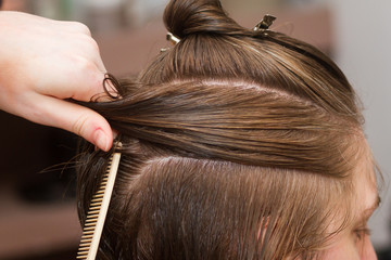 Fototapeta premium hairdresser comb female client's wet hair
