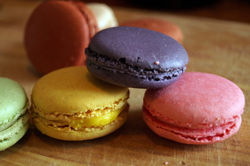 macaroon dessert with colored fillings lie on a wooden table