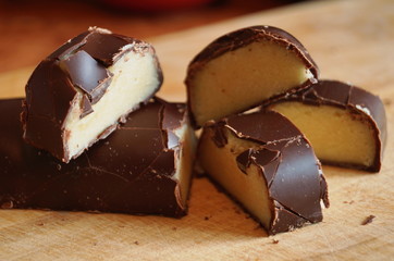 Candy with a marzipan covered with chocolate on a wooden table