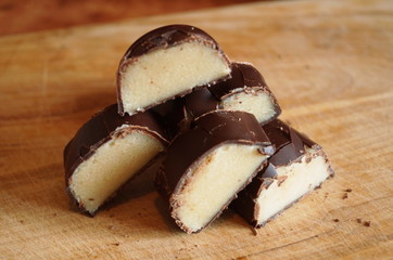 Candy with a marzipan covered with chocolate on a wooden table