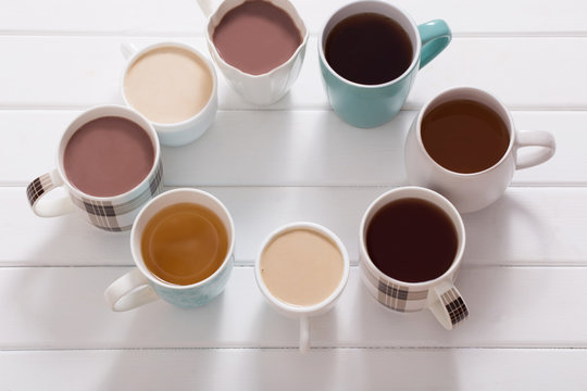 Many cups of  hot drinks on white wooden table