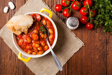 Baked beans in tomato sauce served in yellow, clay bowls.
