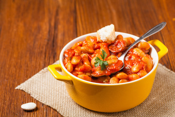 Baked beans in tomato sauce served in yellow, clay bowls.