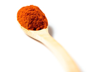 Chili powder in a wooden spoon isolated over white background