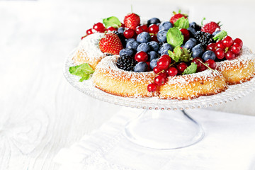 Sponge cake with fresh berries on white table with free text space.