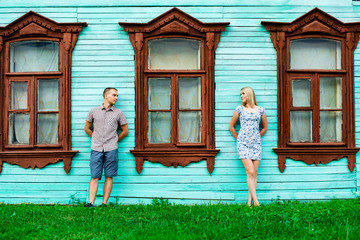 Man and woman standing at home with a large wooden windows, summer in city, event concept of  young family, newlyweds complex relationship. Lifestyle in romance. Outdoors. Old style.