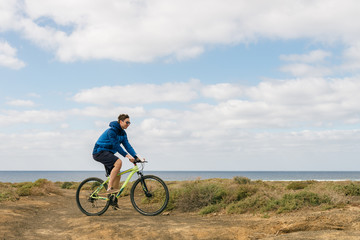 Fototapeta premium handsome man in casual outfit ride a mountain bike on island