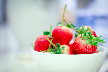 Fresh strawberries in a bowl on table.