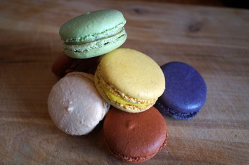 macaroon dessert with colored fillings lie on a wooden table