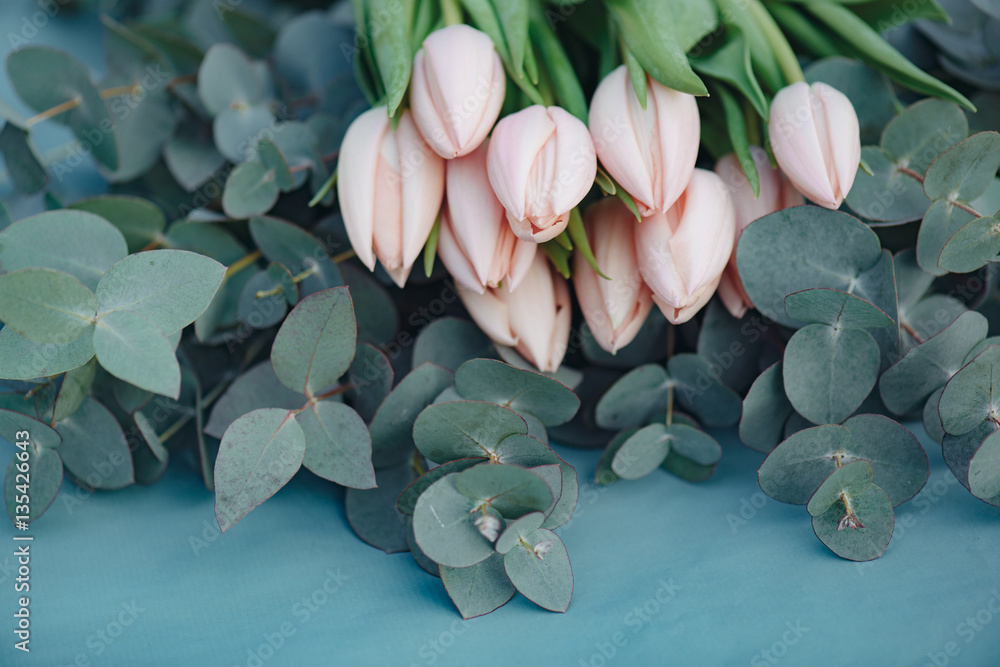 Wall mural flower decoration. fresh pink tulip flowers bouquet on eucalyptus leaves.