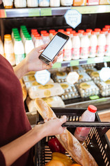Woman doing shopping and using mobile phone in grocery shop