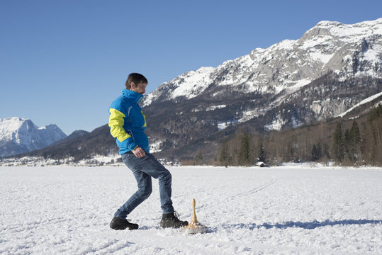 Mann mit Eisstock am See vor Gebirgslandschaft, Bavarian curling