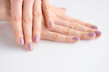 Closeup of hands of a young woman with pink manicure on nails against white background