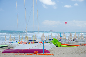 Summer end. Closed umbrellas, closed beach loungers , stormy sea and red flag. No bathers, bathing prohibited