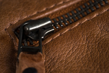 Brown textured leather jacket zippers. Leather jacket macro details. Jacket zippers and pockets
