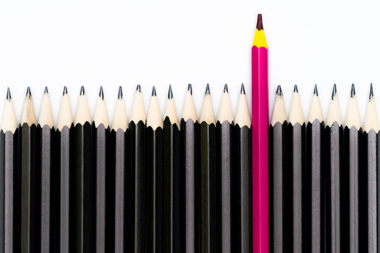 Pinker Buntstift ragt aus der Masse blasser Bleistifte heraus 