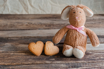 Fluffy toy bunny with cookies in the shape of hearts.  Postcard