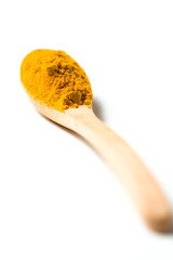 Turmeric powder in a wooden spoon isolated over white background