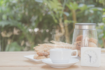 Coffee with smoke and cookie have clock show time 10.30 am background barley rice grains and nature on wood table with copy space. vintage tone.