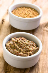 Whole grain mustard and yellow mustard seeds in small bowls, photographed on wood with natural light (Selective Focus, Focus in the middle of the mustard)